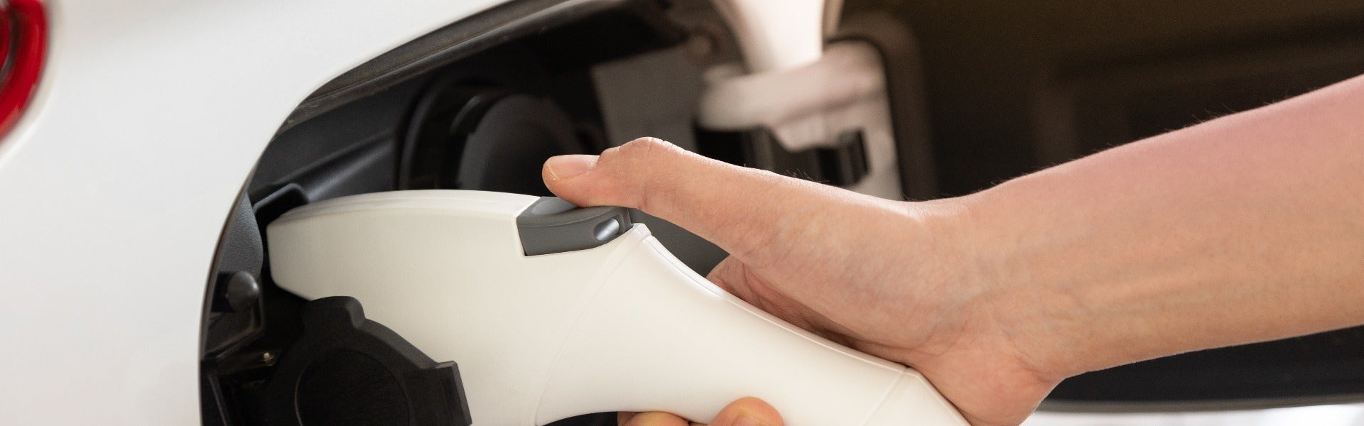 person putting their electric car charger back up at home